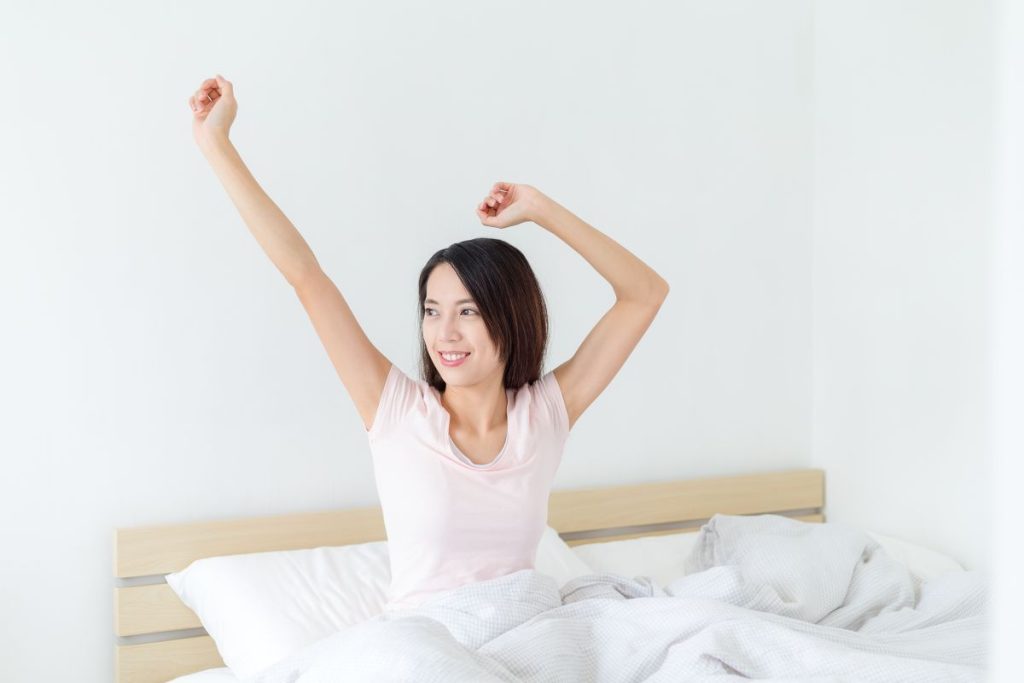 woman happily waking up after a good night sleep
